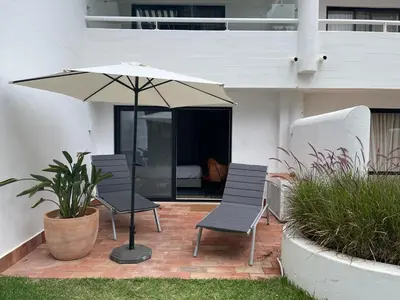 a patio with two chairs and an umbrella at Victory Village 10C in Quinta do Lago