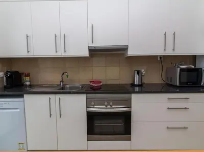 a kitchen with white cabinets and a sink and a microwave at Rainbow House by Stay ici Algarve Holiday Rental in Albufeira
