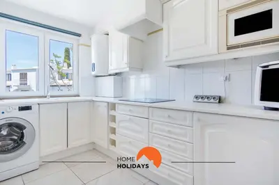 a kitchen with white cabinets and a washer and dryer at #088 T2 São Rafael 64B by Home Holidays in Albufeira