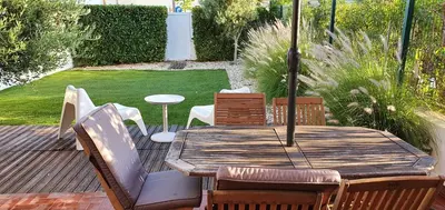 a wooden table with chairs and an umbrella on a deck at Villa charmosa V2 junto à praia e à Marina de Vilamoura in Quarteira