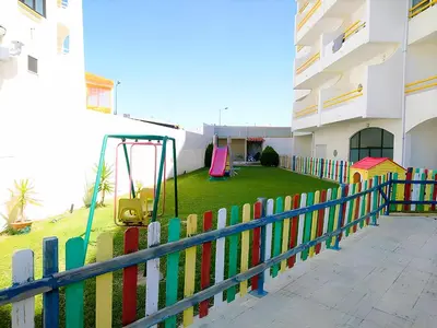 a colorful fence with a playground in front of a building at 1 Bedroom Apartment Chaves, Praceta Vitorino Nemesio, Albufeira in Albufeira