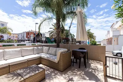 a couch and a table and a umbrella on a patio at BmyGuest - Vilamoura Marina's View in Vilamoura