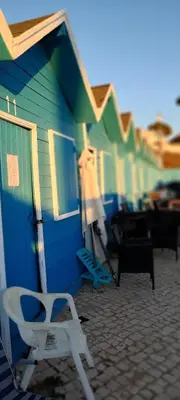 a row of blue and green buildings with a white chair at Lendas de Portugal in Olhos de Água