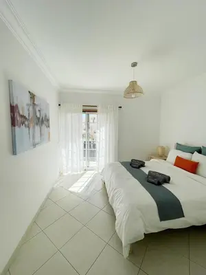 a white bedroom with a large bed and a window at Vitamin Sea Vilamoura in Quarteira
