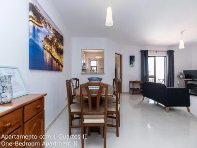 a dining room and living room with a table and chairs at Akisol Albufeira Sunny in Roja- Pé