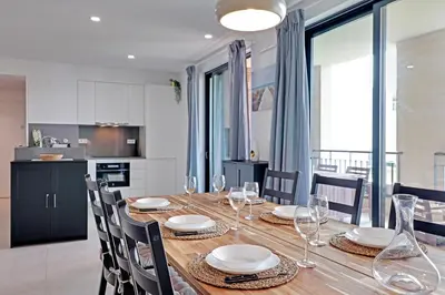 a dining room table with chairs and a kitchen at Andiamo Apartment in Vilamoura