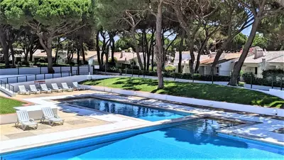 a swimming pool with chairs and trees in a yard at Casinha nas Açoteias in Olhos de Água