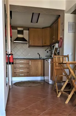 a kitchen with wooden cabinets and a table and chairs at Casinha nas Açoteias in Olhos de Água