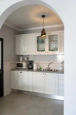 a kitchen with white cabinets and a pendant light at Beach Loft in Quarteira
