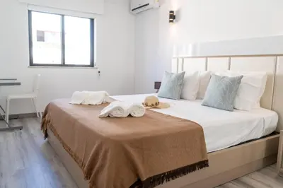a bedroom with a large white bed with towels on it at Beach Loft in Quarteira