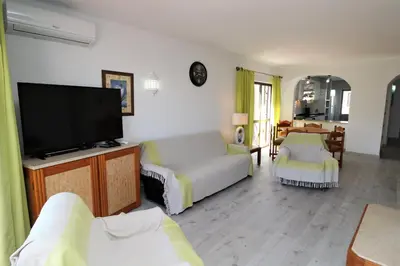a living room with a couch and a flat screen tv at Apartamento T2 Praia de São Rafael Hibiscus 41A - Albufeira, Algarve in Albufeira