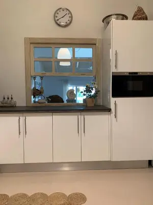a kitchen with white cabinets and a clock on a window at Casa de Férias com piscina - Condominio Vilamouraténis in Vilamoura