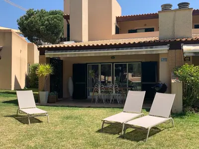 a group of chairs sitting in the grass in front of a house at Casa de Férias com piscina - Condominio Vilamouraténis in Vilamoura