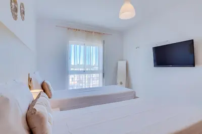 a white bedroom with a bed and a television at AL - Quarteira Old Town in Quarteira