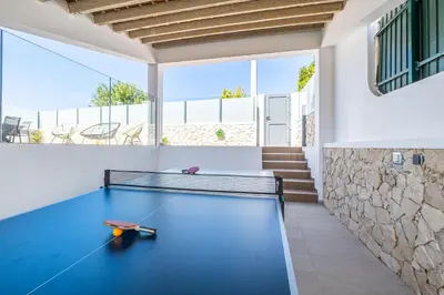 a ping pong table in a room with a stone wall at Atlantis Luxury Villa by Atlantic Places in Albufeira