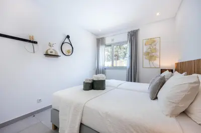 a white bedroom with a large bed and a window at Casa Salty in Albufeira