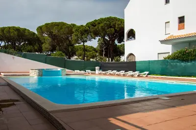 a swimming pool with chairs and a building at Açoteias B3 in Albufeira
