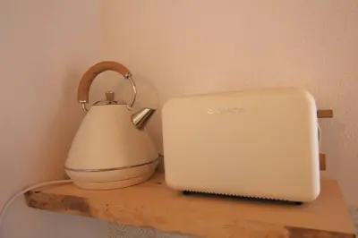 a tea kettle on a wooden shelf next to a laptop at Vila Lobo Algarve in Faro