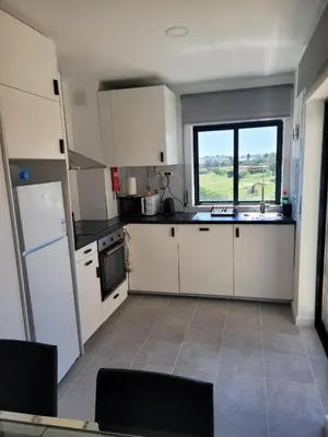 a kitchen with white cabinets and a sink and a window at Apartamento T1 Salgados in Guia