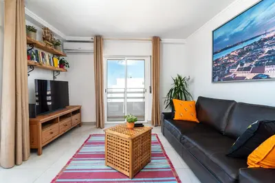 a living room with a couch and a television at Faro Center Stunning View in Faro