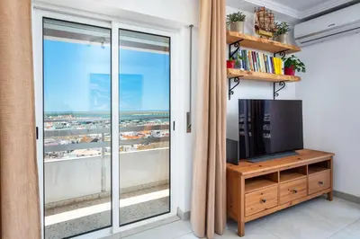 a living room with a tv and a large window at Faro Center Stunning View in Faro
