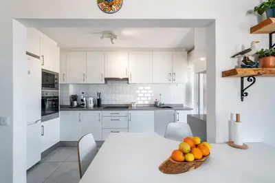 a white kitchen with a table with a bowl of fruit at Faro Center Stunning View in Faro