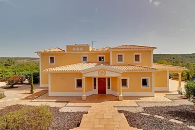 a large yellow house with a red door at Casa do Pomar by Portucasa in Alte