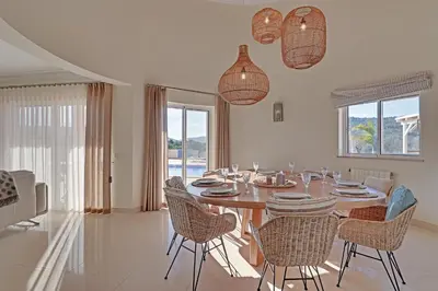 a dining room with a wooden table and chairs at Casa do Pomar by Portucasa in Alte