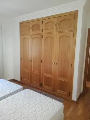 a bedroom with wooden cabinets and a white bed at Villa V2 U in Olhos de Água