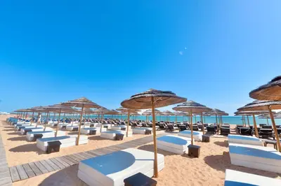 a bunch of chairs and umbrellas on a beach at Villa Cove - Villa in complex only 5 minutes from the Marina of Vilamoura in Quarteira