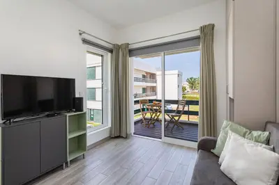 a living room with a couch and a television and a balcony at Centralgarve - Elegant and Cosy Studio in the Heart of Vilamoura - Aldeia do Mar T0 in Vilamoura