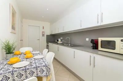 a kitchen with a table with chairs and a microwave at Vilamoura Apartment Jacaranda - By Dalma Portuguesa in Vilamoura