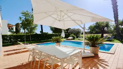 a white table and chairs with an umbrella next to a pool at Vila Castro-Cleverdetails, Quiet area, private pool in Vilamoura