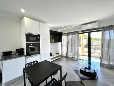a kitchen with white cabinets and a black table and chairs at Topazio - Pool & near the center by HD PROPERTIES in Vilamoura
