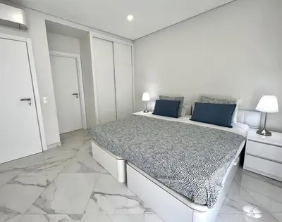 a white bedroom with a large bed with blue pillows at Aman - Near the beach by HD PROPERTIES in Quarteira