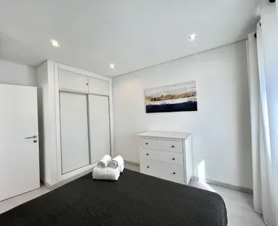 a white bedroom with a bed and a dresser at Nancy Apartment - Near Vilamoura Marina by HD PROP in Vilamoura