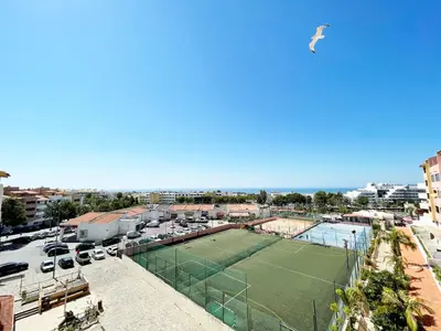 a tennis court in a parking lot with cars at Panoramic Seaview - 2 Bedroom, Main Ave, 15 Min Walk Beach, Workspace in Albufeira