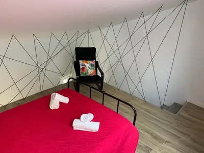 a bedroom with a red bed with two white towels at CASA DAS CEGONHAS in Faro