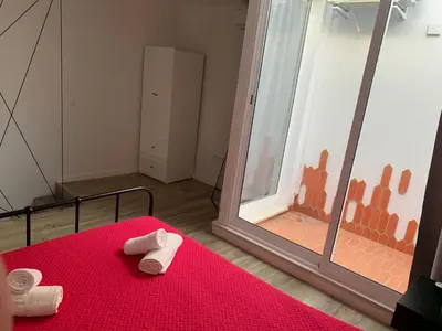 a bedroom with a red bed and a large window at CASA DAS CEGONHAS in Faro