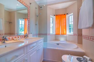 a bathroom with two sinks and a tub and a mirror at Oceans 8. in Almancil