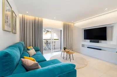 a living room with a blue couch and a flat screen tv at Apartamento Centro de Albufeira Sunny in Albufeira