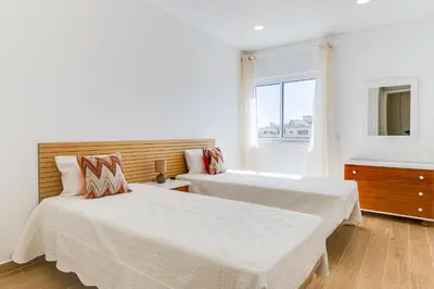 two beds in a white room with a window at T1 Albufeira city centre in Albufeira