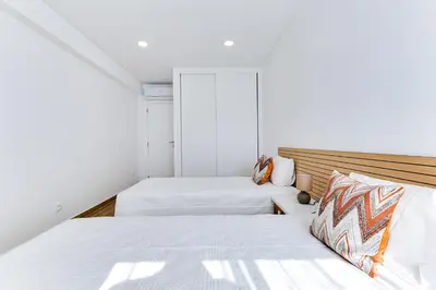 two beds in a small room with white walls at T1 Albufeira city centre in Albufeira