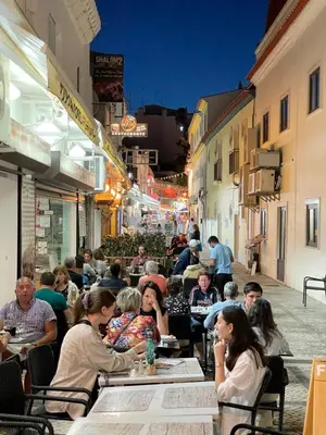 a group of people sitting at tables in a restaurant at FeWo Cesar Manrique - Albufeira, Portugal in Albufeira