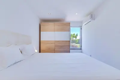 a white bedroom with a large bed and an open door at AL - Barracuda Village in Vilamoura