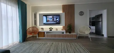 a living room with two chairs and a television on a wall at Beach View Vela House in Albufeira