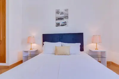 a bedroom with a large white bed with two lamps at AL - Colina Beach Holidays in Quarteira