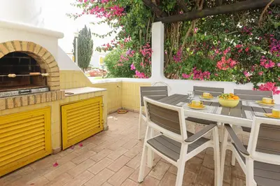 a patio with a table and chairs and a pizza oven at Villa Aldeia do Golf - BY BEDZY in Vilamoura