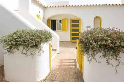 a yellow door on a white house with flowers at Villa Aldeia do Golf - BY BEDZY in Vilamoura