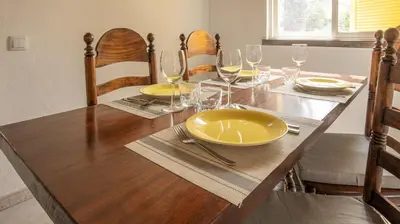 a dining room table with yellow plates and wine glasses at Villa Aldeia do Golf - BY BEDZY in Vilamoura